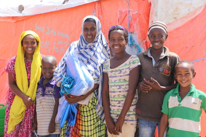 Meriam holding a pair of plastic sheet and rope with her family at her home in Somali region