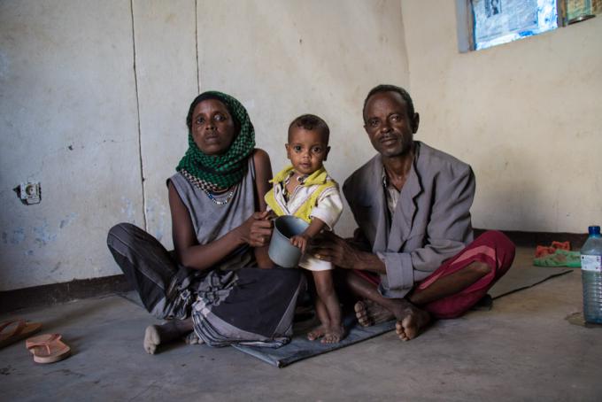 Emnet* and her husband, Yohannes* sit on the floor of their home with their one-year-old boy, Tita*, who has moderate acute malnutrition.